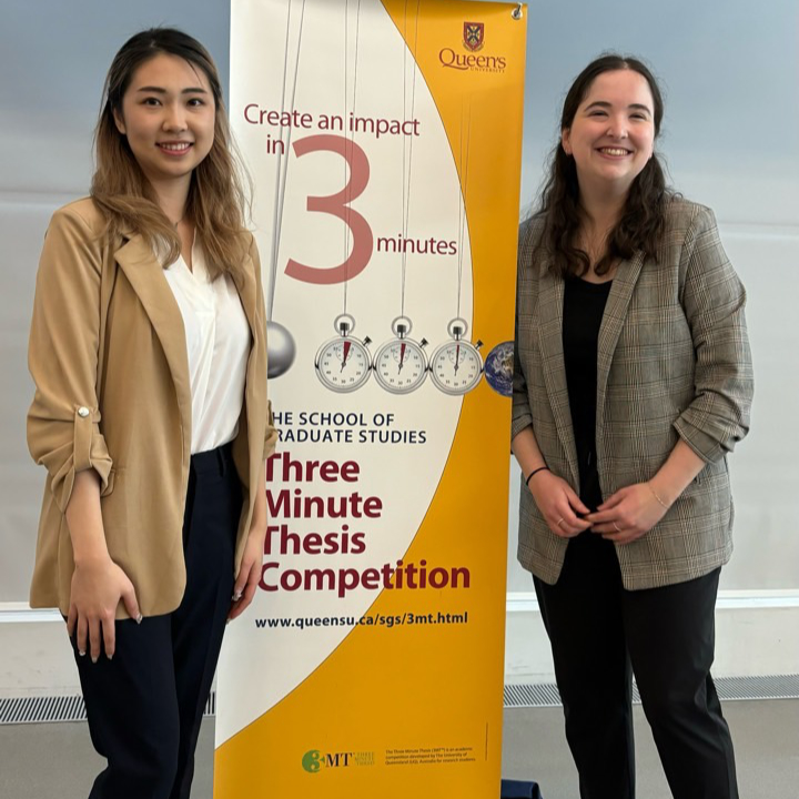 Sarah and Sara in front of the 3MT banner