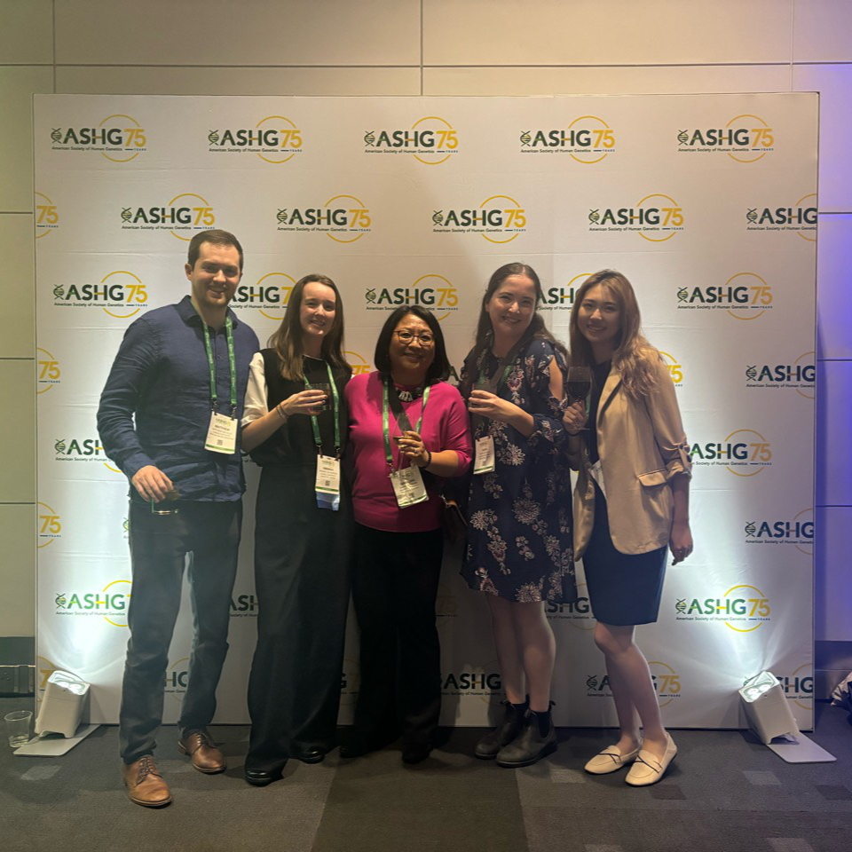The lab members in front of an ASHG-themed background